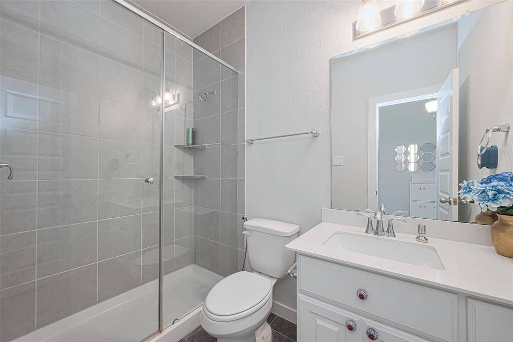 A full guest bathroom nearby offers a spacious glass shower.