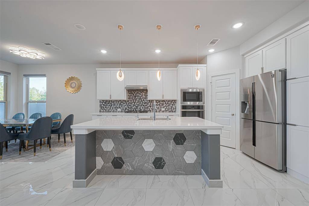 repare to be amazed in the dream kitchen—a culinary masterpiece featuring a statement island with decorative tilework, quartz countertops, dazzling backsplash, built-in stainless-steel appliances, a 5-burner cooktop, single oven, pendant lighting, and ample cabinetry.