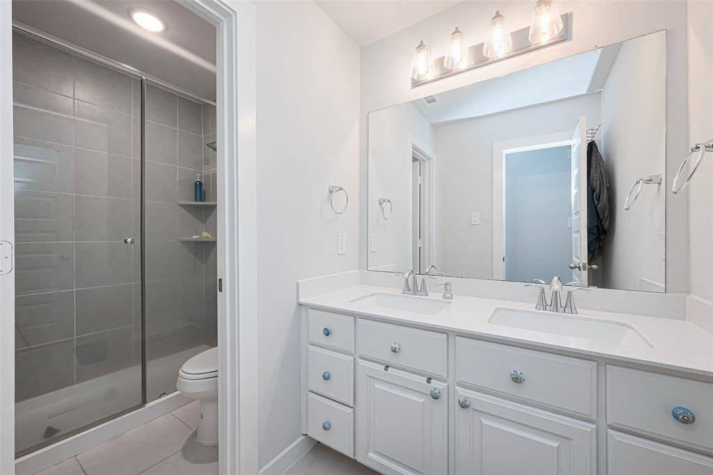 A well-appointed full bathroom with double sinks and a walk-in shower.