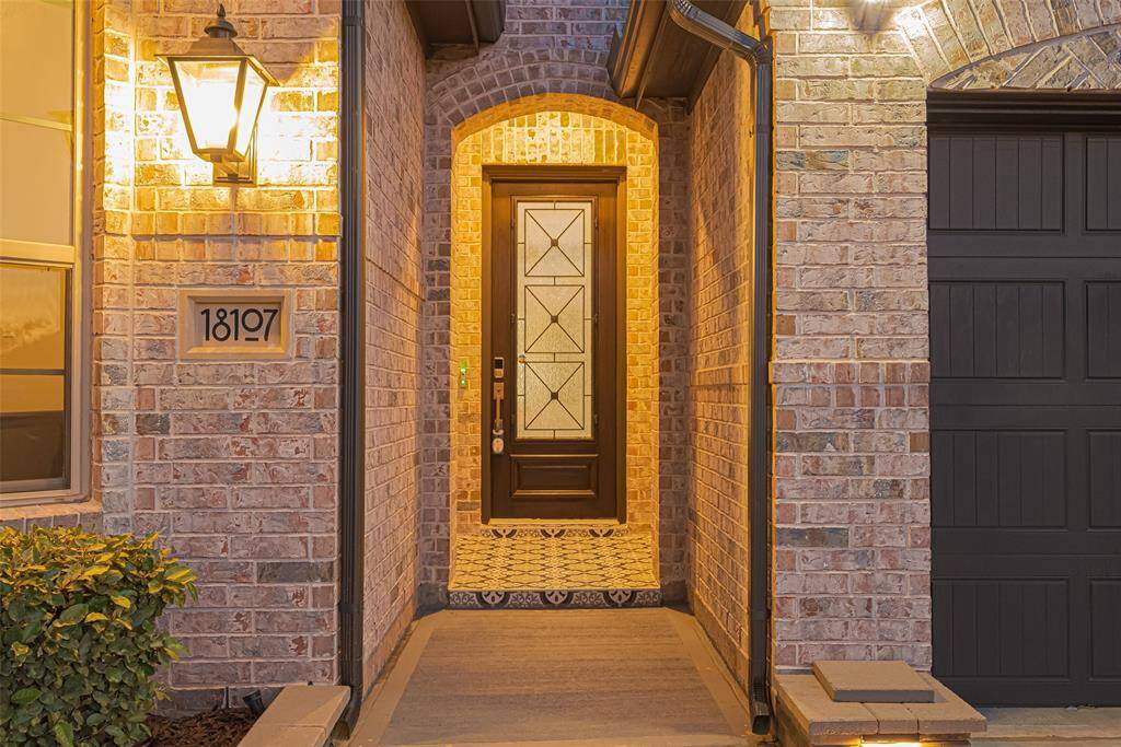 A classy wood and glass front door that sets the tone for the elegance inside. The tile-paved porch welcomes guests with charm and sophistication.