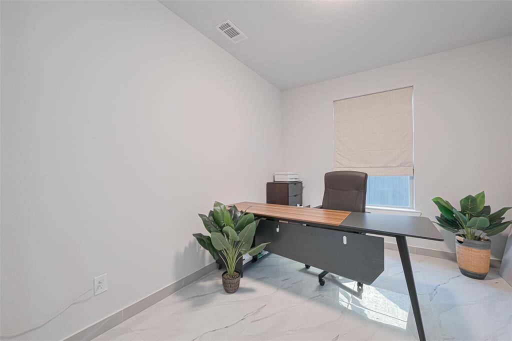 The dedicated home office features double glass French doors and custom window shades, offering a serene workspace.