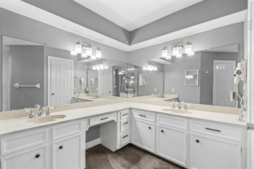 This bathroom features a spacious double-sink vanity with modern fixtures and ample storage. It has large mirrors and bright lighting, creating a clean and contemporary feel.