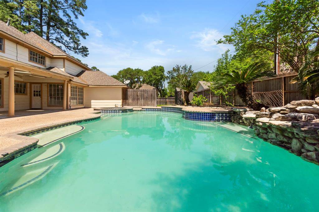 This photo showcases a spacious backyard with a large swimming pool, surrounded by a stone border and lush greenery, perfect for relaxation and entertaining.