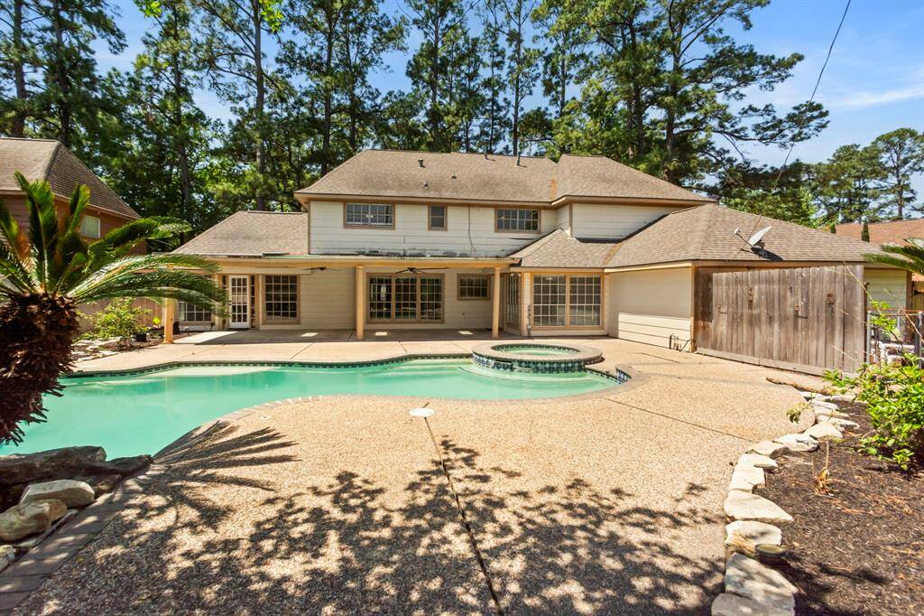 This spacious two-story home features a large backyard with a swimming pool and spa, surrounded by lush trees for privacy. The exterior includes a covered patio, perfect for outdoor entertaining.