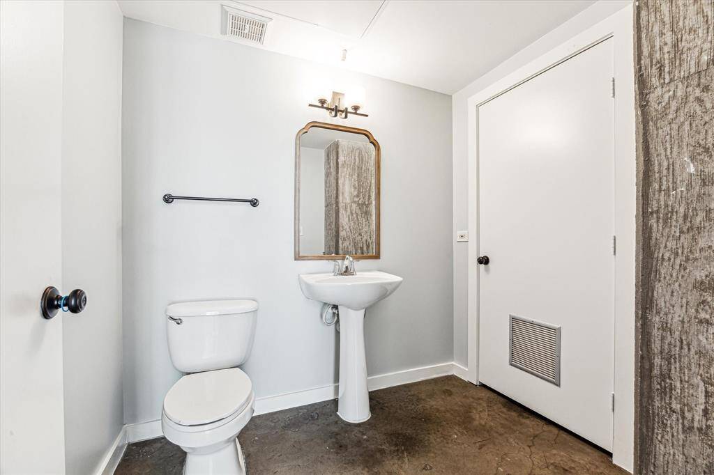 This bathroom features a modern design with a pedestal sink, a toilet, and a wall-mounted mirror. It has a neutral color palette and a clean, minimalist look.
