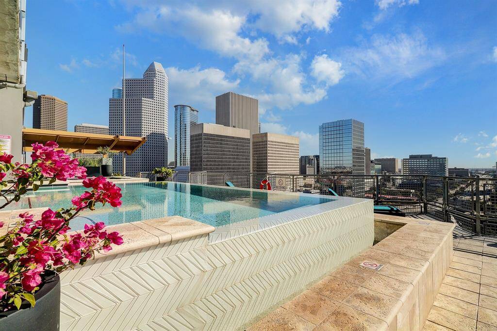This photo showcases a modern rooftop pool with stunning city skyline views, featuring elegant tiling and vibrant flowers, perfect for urban living.