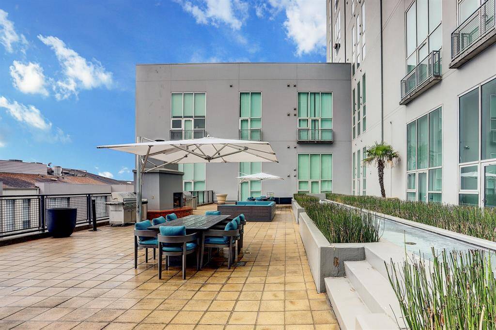 This photo showcases a spacious outdoor terrace with modern seating, a dining area, umbrellas, and greenery. Ideal for entertaining, it offers a stylish, open-air experience with city views.