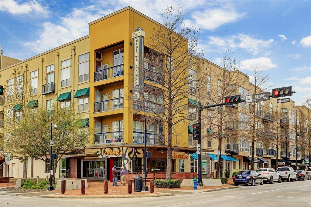 Modern urban apartment complex in a vibrant neighborhood, featuring storefronts at street level and ample natural light from large windows. Ideal for those seeking convenient city living with nearby amenities.