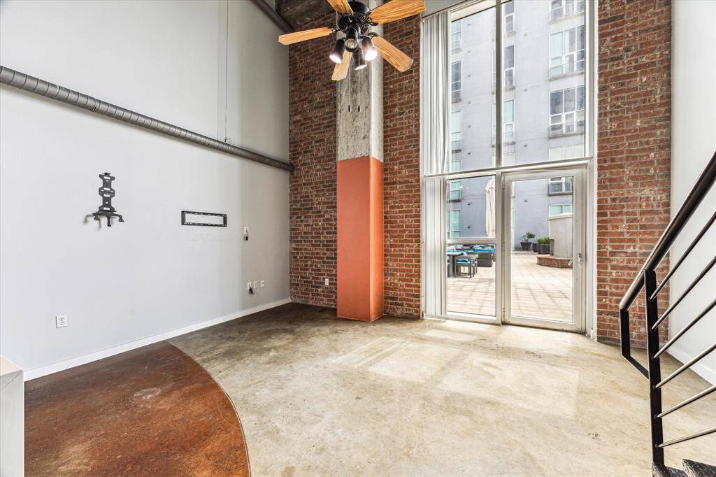 This modern loft features high ceilings, exposed brick walls, and large windows that offer access to a spacious outdoor terrace, providing an industrial yet cozy atmosphere.