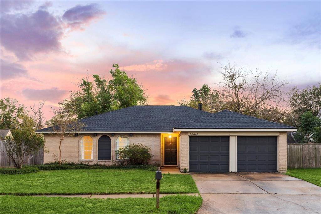 This beautifully updated home in Sundown, Katy, TX, features a fresh roof, new remote garage door openers, and a warmly lit entryway. The front yard and double driveway enhance its curb appeal. Set against a stunning sunset, this home is both stylish and inviting.