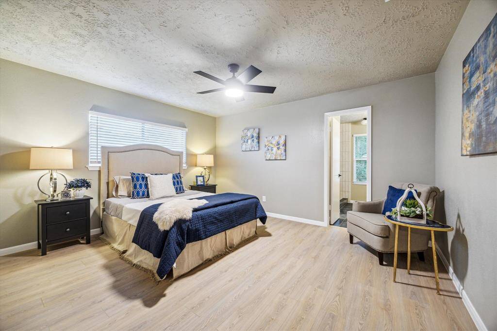 The spacious primary suite offers a serene retreat with modern tones, elegant lighting, and ceiling fan. A private ensuite bath provides convenience, while large windows fill the space with natural light. Stylish finishes and a functional layout make this bedroom both inviting and comfortable.