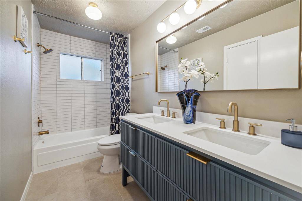 The updated guest bathroom has dual vanity and shower/tub combo.