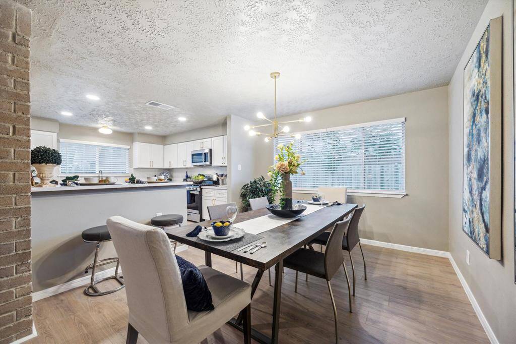 This bright and airy dining area offers a seamless connection to the updated kitchen. Large windows bring in natural light, while the modern chandelier adds a stylish touch. The open bar seating and spacious layout make it perfect for both casual meals and entertaining.