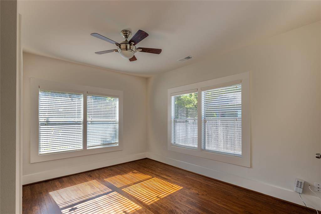 Bedroom with ceiling fan and wood flooring.
