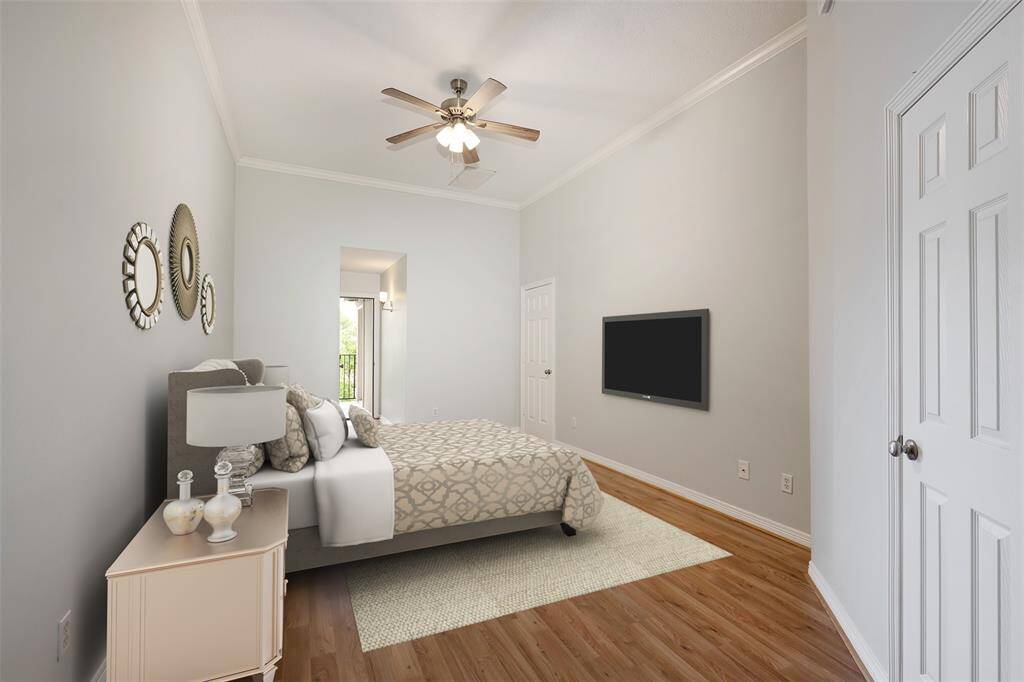 The third-floor primary bedroom features wood floors, vaulted ceilings, arched windows, and access to 2 covered balconies! Virtually staged photo.