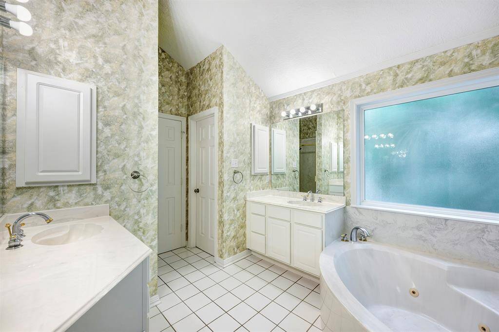 Primary bathroom with two vanities and a deep tub.