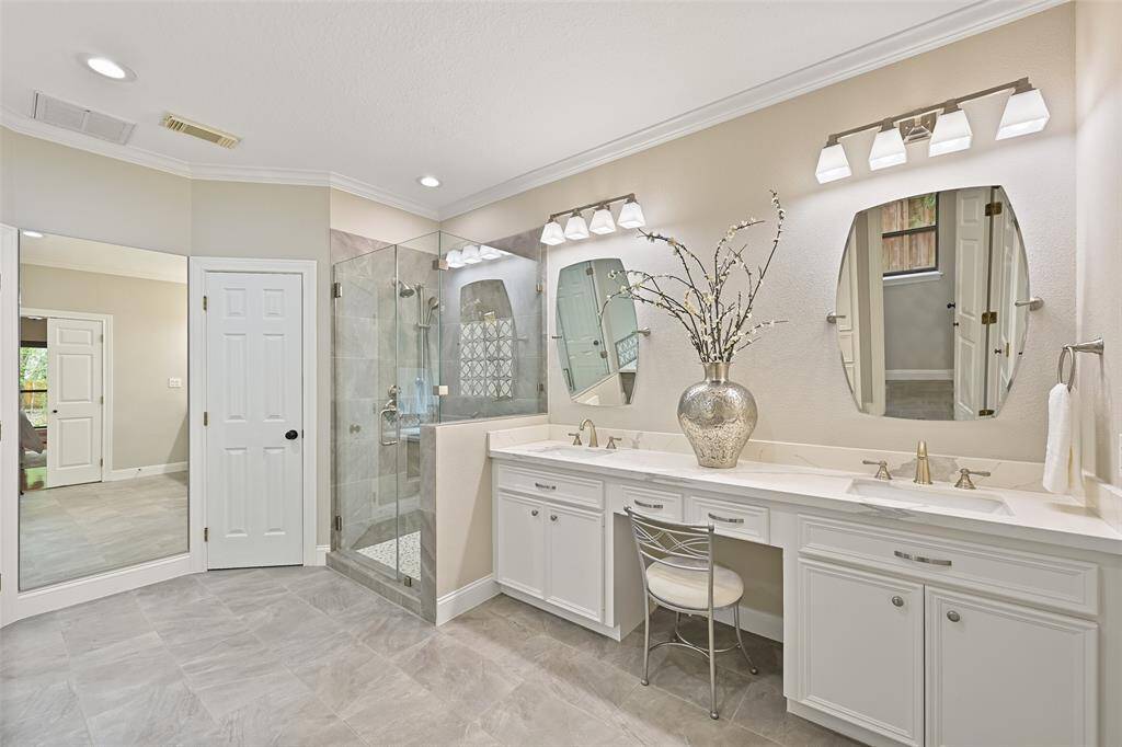 The master bathroom was beautifully renovated in 2020 to include a lengthy seated vanity with quartz countertops and dual rectangular basin sinks, stylish mirrors & lighting, tile floors, and separate his & hers walk-in closets.