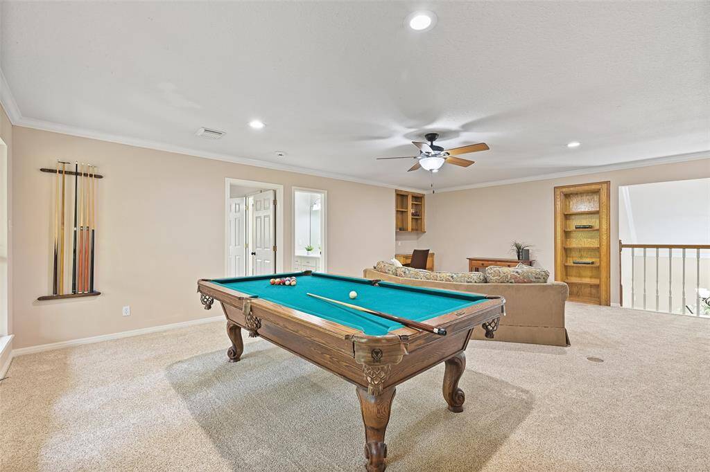 Head upstairs to the centrally located second-floor game room and you'll find a built-in desk station, a lighted ceiling fan, recessed lights, plush carpet with convenient floor plugs, a bookshelf that functions as a concealed entrance to attic storage, and a breezy balcony with backyard views.