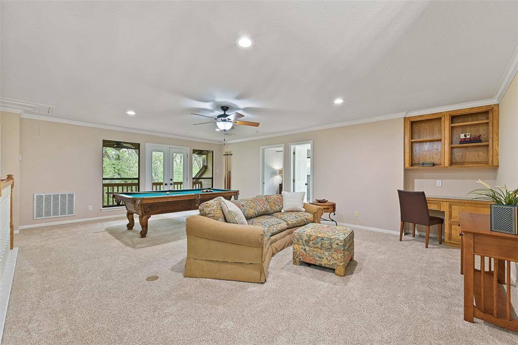 Head upstairs to the centrally located second-floor game room and you'll find a built-in desk station, a lighted ceiling fan, recessed lights, plush carpet with convenient floor plugs, a bookshelf that functions as a concealed entrance to attic storage, and a breezy balcony with backyard views.