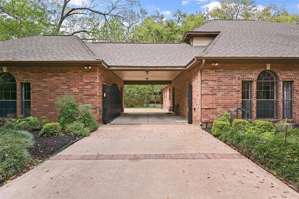 A lengthy concrete driveway winds from the cul de sac street past a deeply wooded front treelined into a manicured front yard with freshly mulched beds, an in-ground sprinkler system, and an automatic gate at the port cochere that turns into an oversized parking pad & a rear-facing 3-car garage.