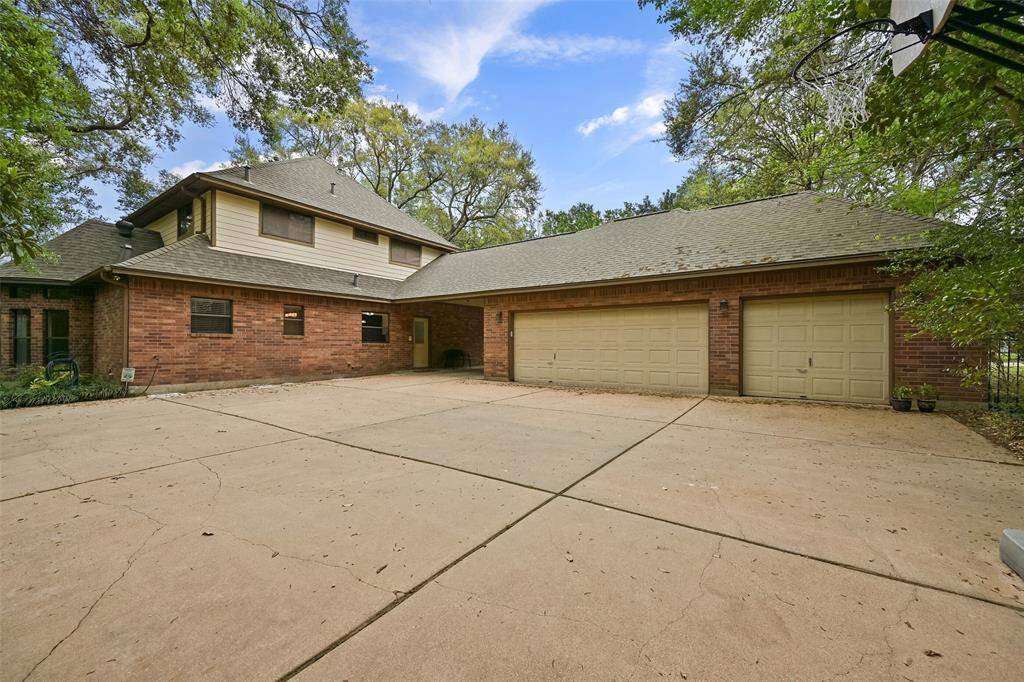 Parking space abounds, including a lengthy driveway leading to an automatic gate at the pass-through port cochere area that then spills out onto this oversized parking pad and rear entrance 3-car garage. Inside the garage, note the workshop area, ample storage, & vacuum system.