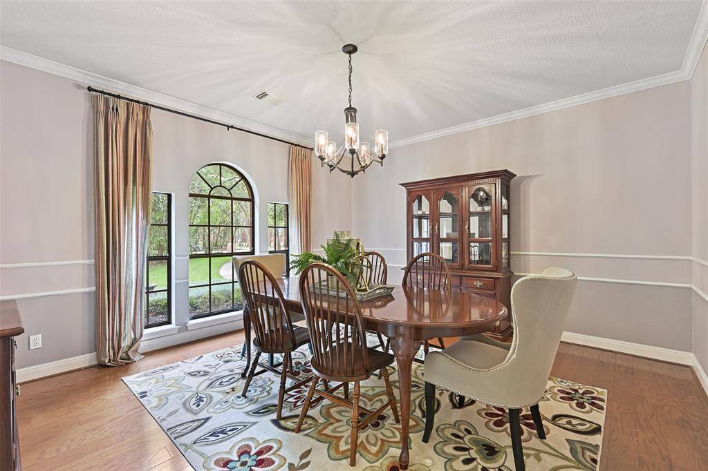 Entertain in style in this formal dining room with handsome wood floors, elegant moldings, stylish lighting, direct kitchen access, and a trio of palladium arched windows that overlook the private and park-like front yard.