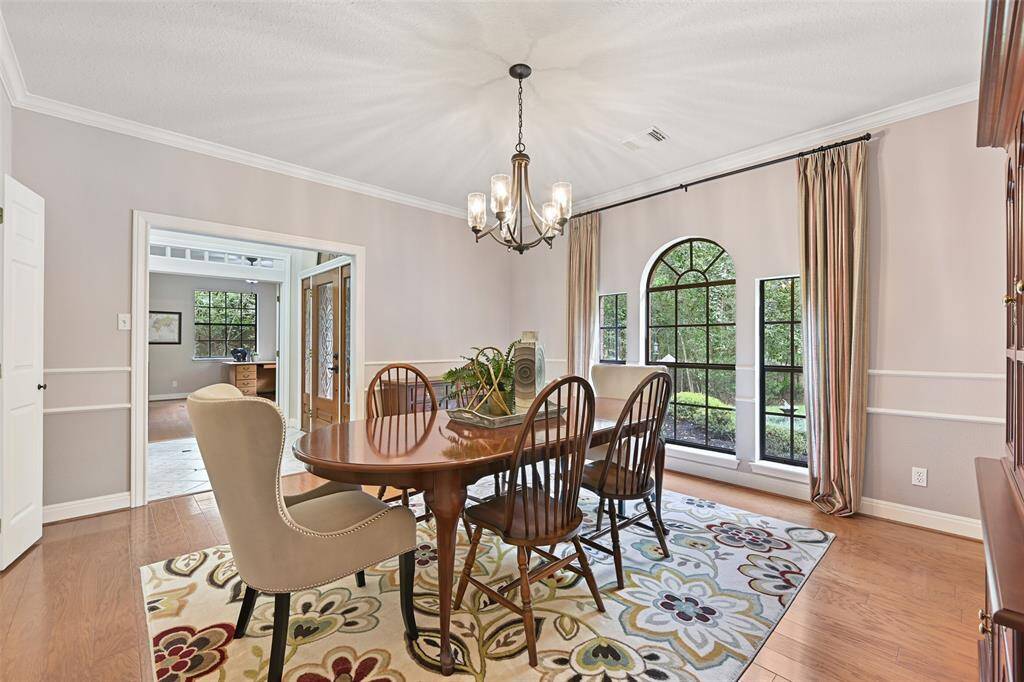 Entertain in style in this formal dining room with handsome wood floors, elegant moldings, stylish lighting, direct kitchen access, and a trio of palladium arched windows that overlook the private and park-like front yard.
