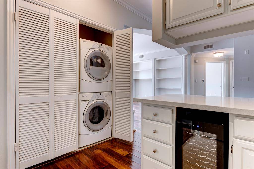 This photo showcases a modern laundry area with a stacked washer and dryer neatly enclosed behind louvered doors.