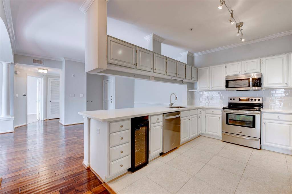 This modern kitchen features spacious cabinetry, stainless steel appliances, and a large quartz countertop, perfect for cooking and entertaining.