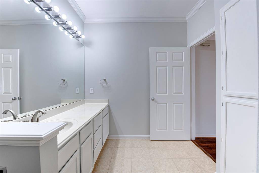 This bathroom features a large vanity with ample cabinet space, a wide mirror with bright lighting, and a neutral color palette for a clean, modern look.
