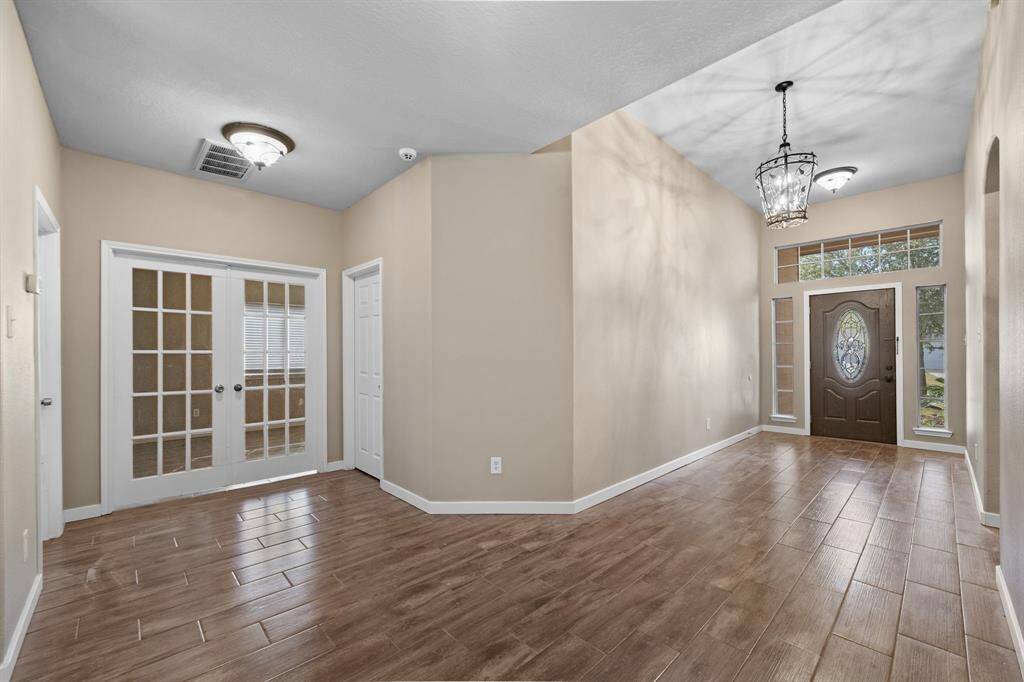 Wide open foyer that leads to the office/study with french doors.  To the right is the laundry room and garage entrance.  To the left is the primary bedroom.