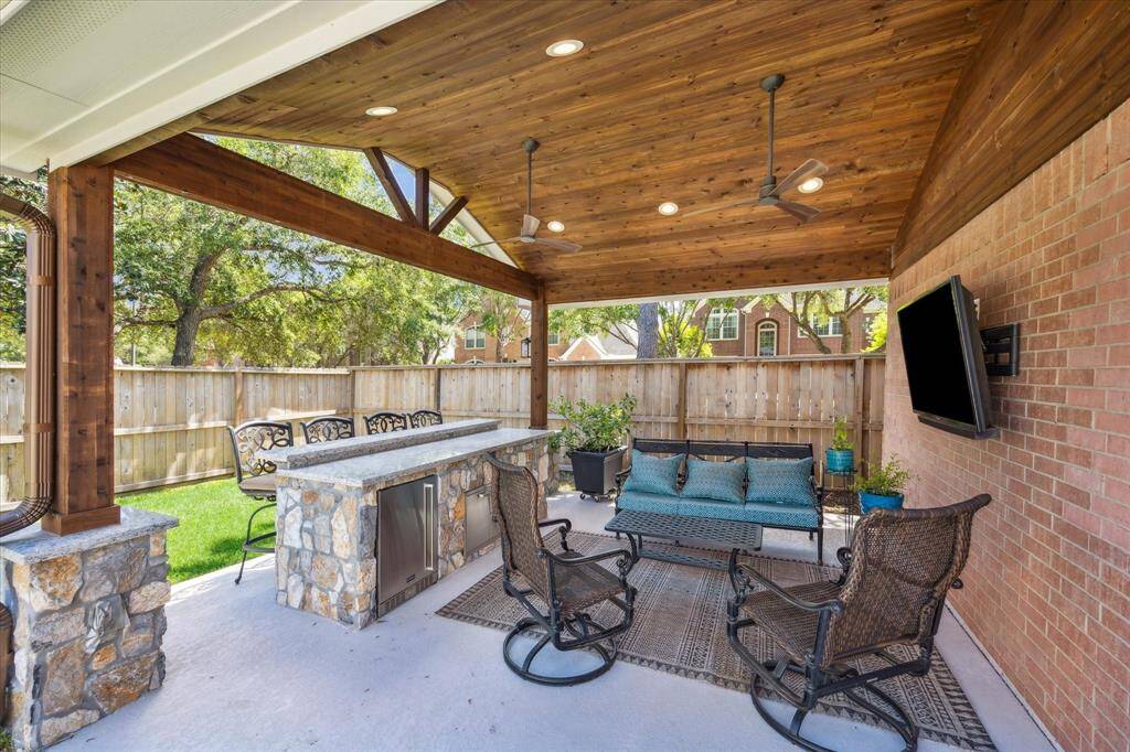 COVERED PATIO  Entertaining flows outside to the covered patio.  No expense was spared during the construction of this addition.  From the high beadboard ceiling hang two modern ceiling fans for keeping cool.  Stone detail on the collumn bases match the bar area.  Full upgraded gutter sytem with gutter guards surround the home.