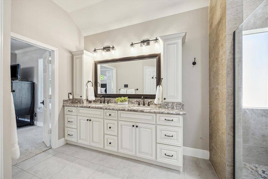 ALTERNATE VIEW OF PRIMARY BATH  Dual sinks and storage cabinets make the bath functional and tidy.