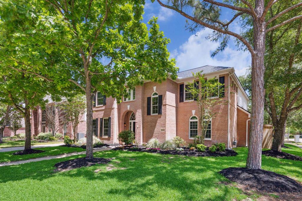 SIDE ELEVATION  Canopies of mature trees dot the border of the large corner lot.  Flowering landscaping fill the beds embracing the home.