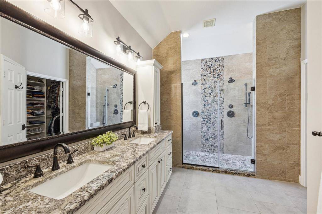 PRIMARY BATHROOM  Updated to the hilt with slab granite countertop, tasteful large format tile flooring and a colossal shower with two shower heads and bench seating.