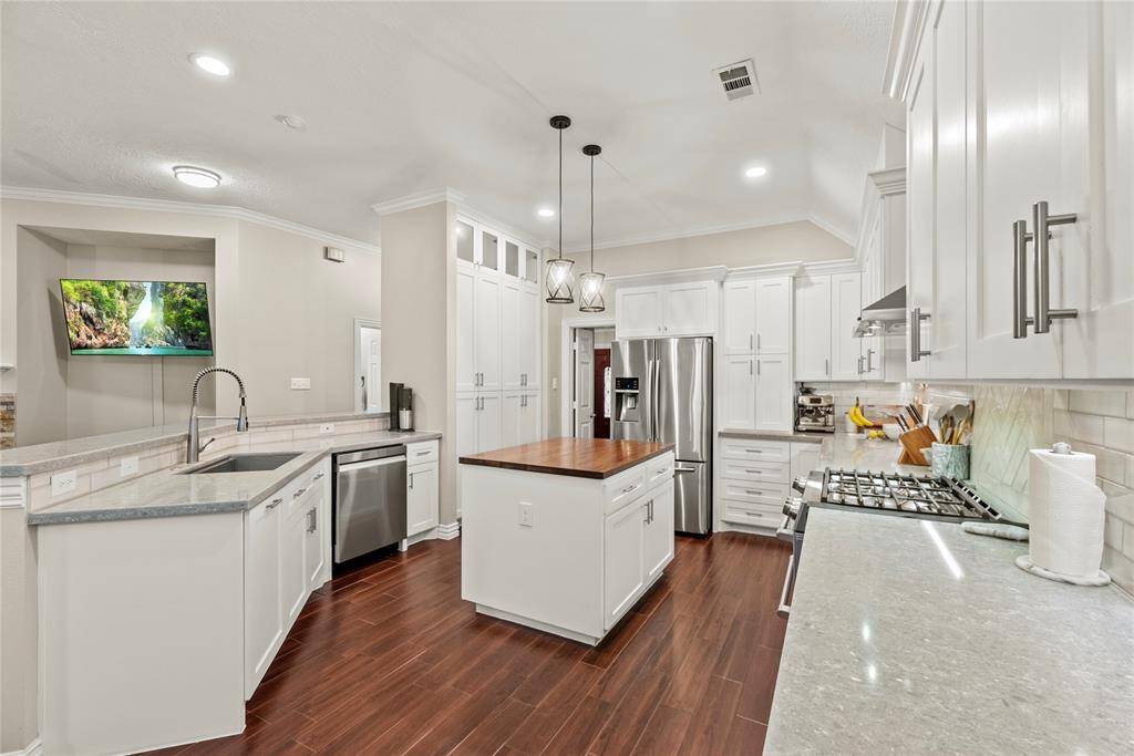 Your chef inspired kitchen awaits! Features include quartz countertops paired with a coordinating backsplash, stainless steel appliances, crisp white cabinets with updated hardware, under cabinet lighting, recessed lighting, and a sprawling island with breakfast bar seating.