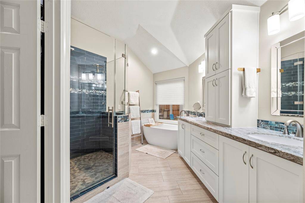 The primary bath features exquisite dual vanities, providing ample personal space along with an abundance of custom cabinetry for seamless organization.