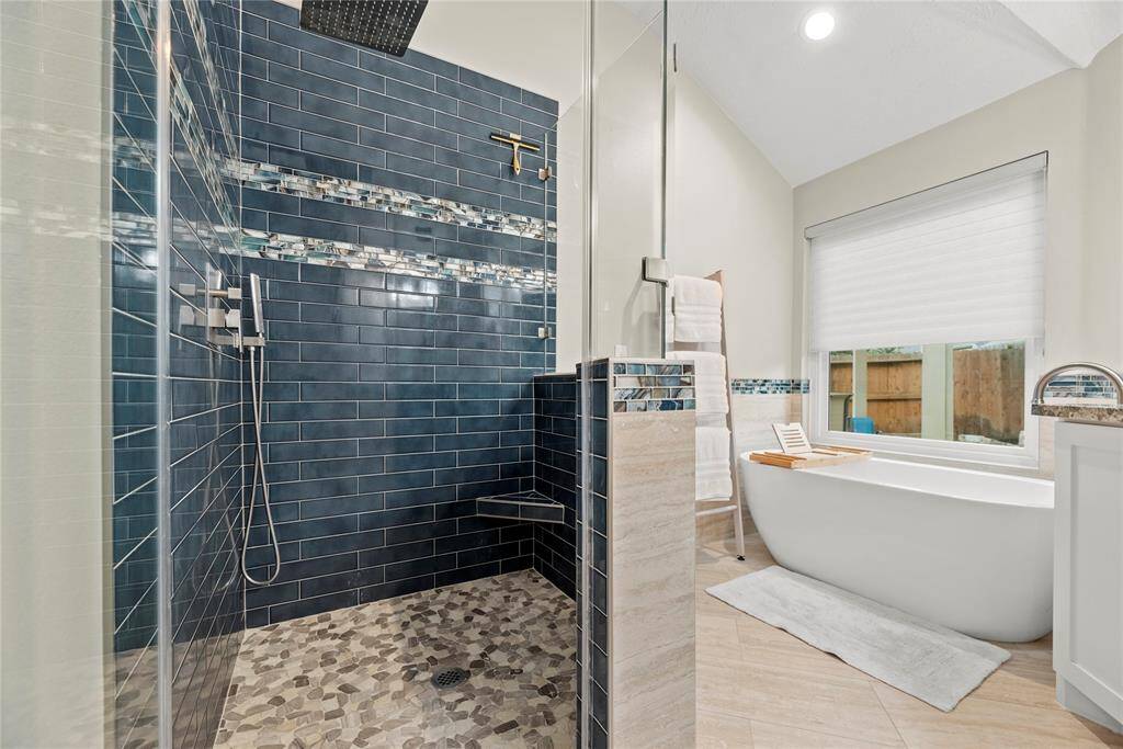The expansive walk-in shower, adorned with stunning tile work and a sleek glass front, offers a luxurious escape for a quick rinse or a refreshing retreat.