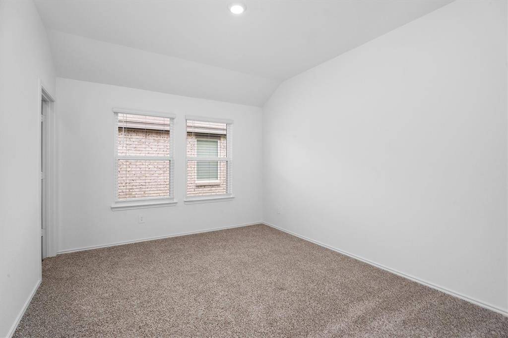 Serene primary retreat with soft carpeting, tall ceilings, and dual windows providing privacy and filtered light.