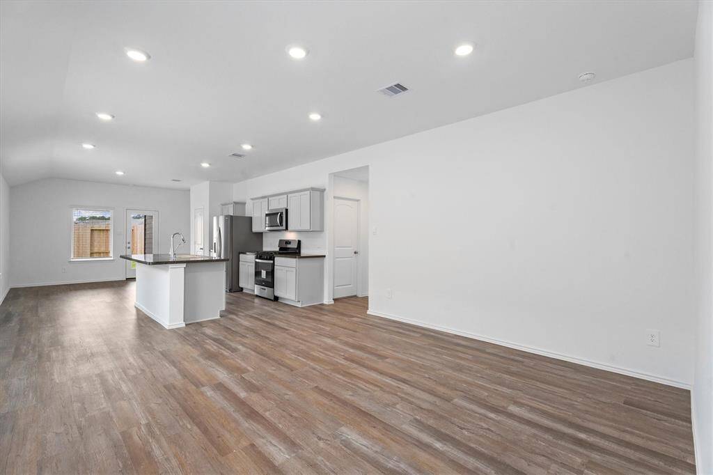 Bright and airy open-concept space with durable luxury vinyl plank flooring and a neutral palette. The layout effortlessly blends living, dining, and kitchen areas, maximizing space and natural light.