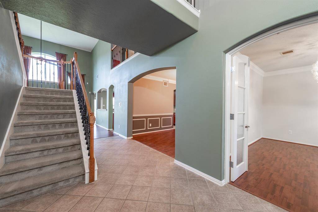 Upon entry, a beautiful staircase and elegant tile flooring lead you seamlessly to the inviting family room.