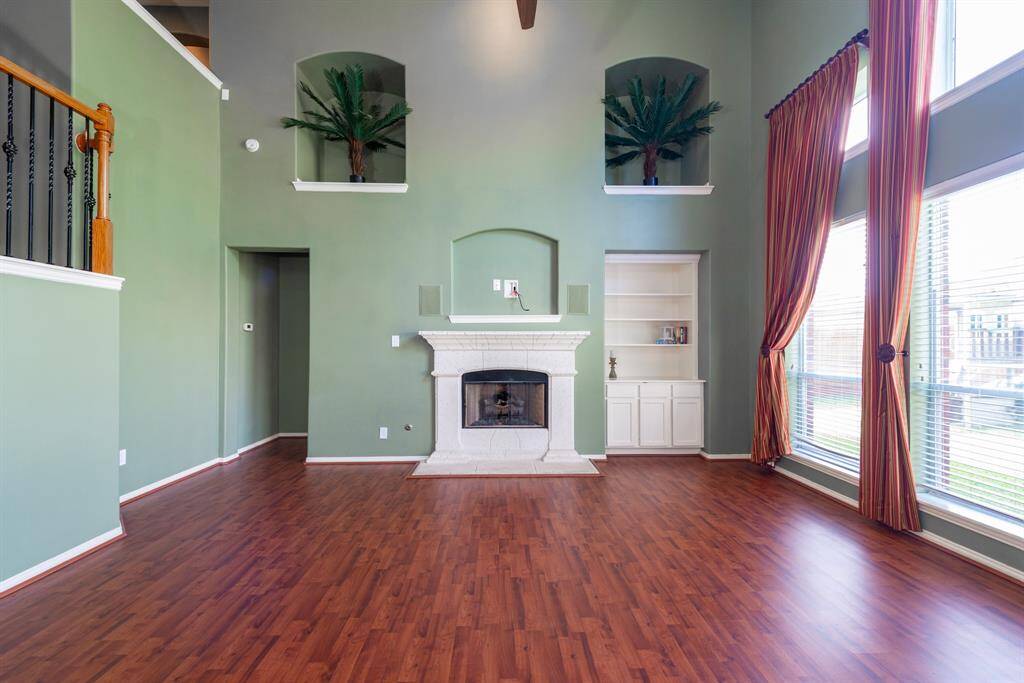 Spacious family room featuring elegant art niches, a cozy fireplace, and a built-in bookcase.