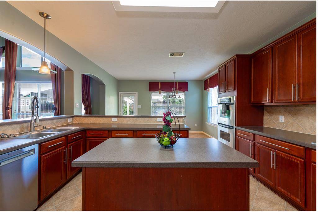 Here's a concise and compelling rewrite:"Enjoy a spacious kitchen with a large island, overlooking an inviting breakfast room. Features include under-cabinet lighting and elegant above-cabinet accents.