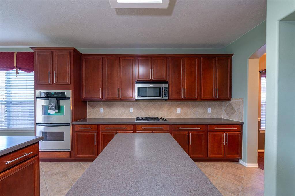 Elegant cabinetry enhances this spacious kitchen, featuring a gas stovetop and double ovens.