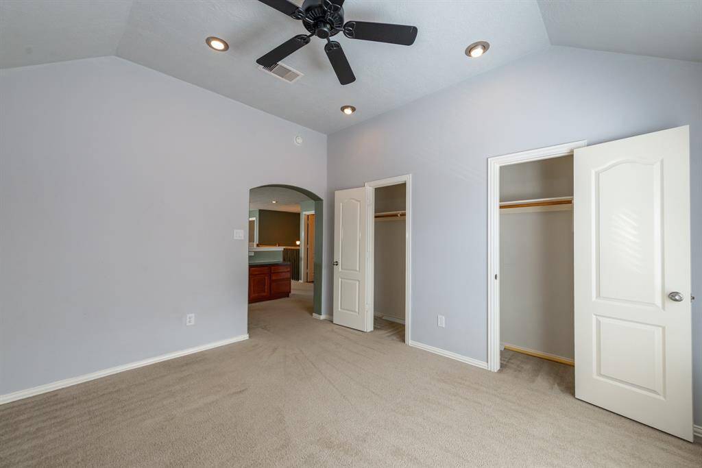 Spacious bedroom with dual closets and stylish archway .
