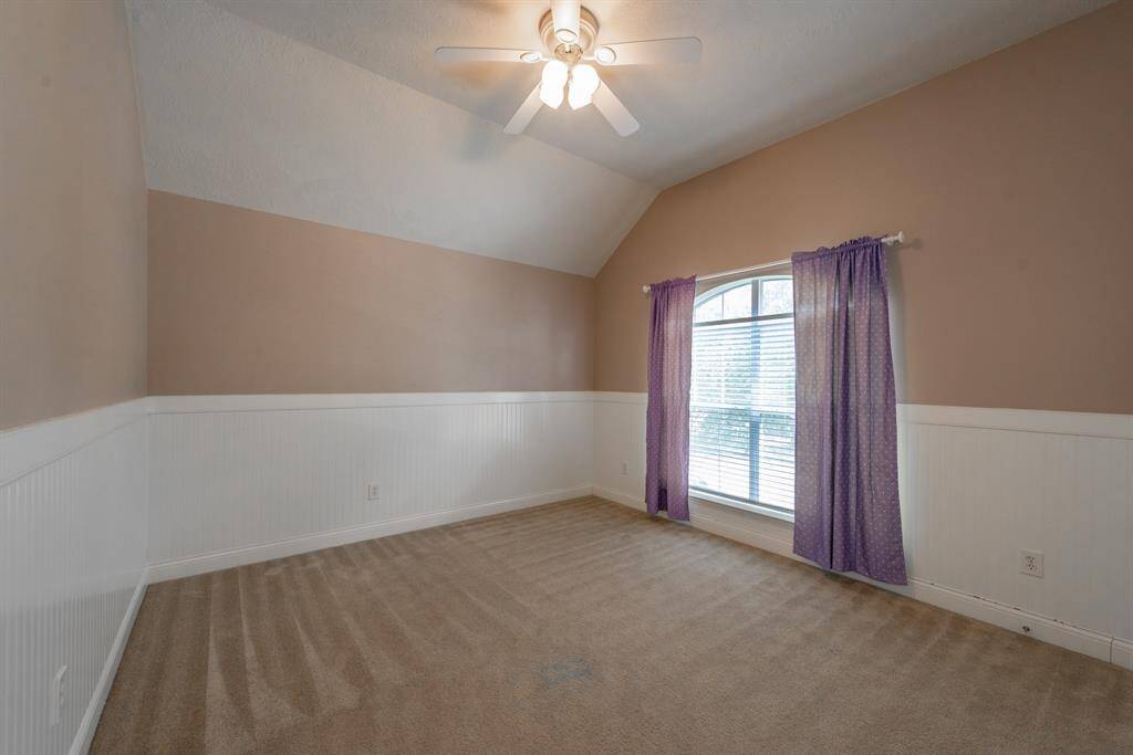 Bright upstairs bedroom with cozy carpeting and charming wainscoting.