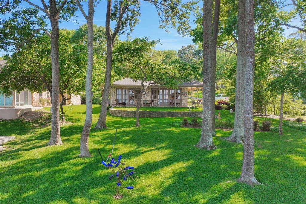 The yard is spacious, shaded by the trees and beautifully landscaped