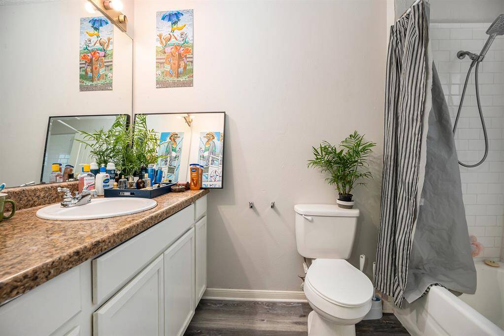 Primary Bathroom Oasis with granite countertops, delicate white cabinetry and tub shower with tile surround.