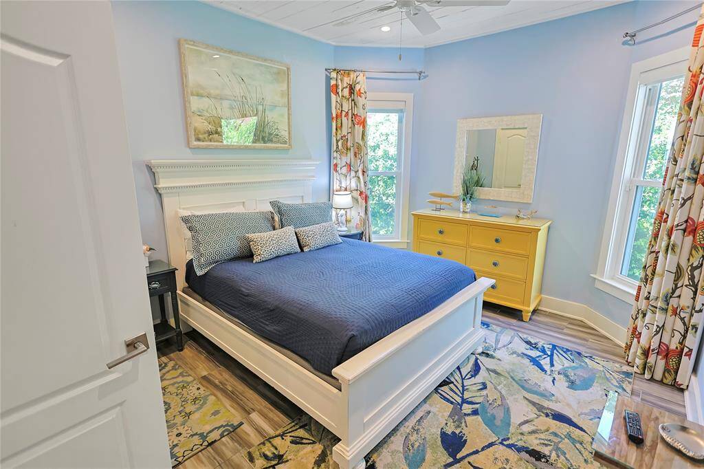 Cozy bedroom with lots of natural light streaming in through two large windows, enhancing the airy feel.