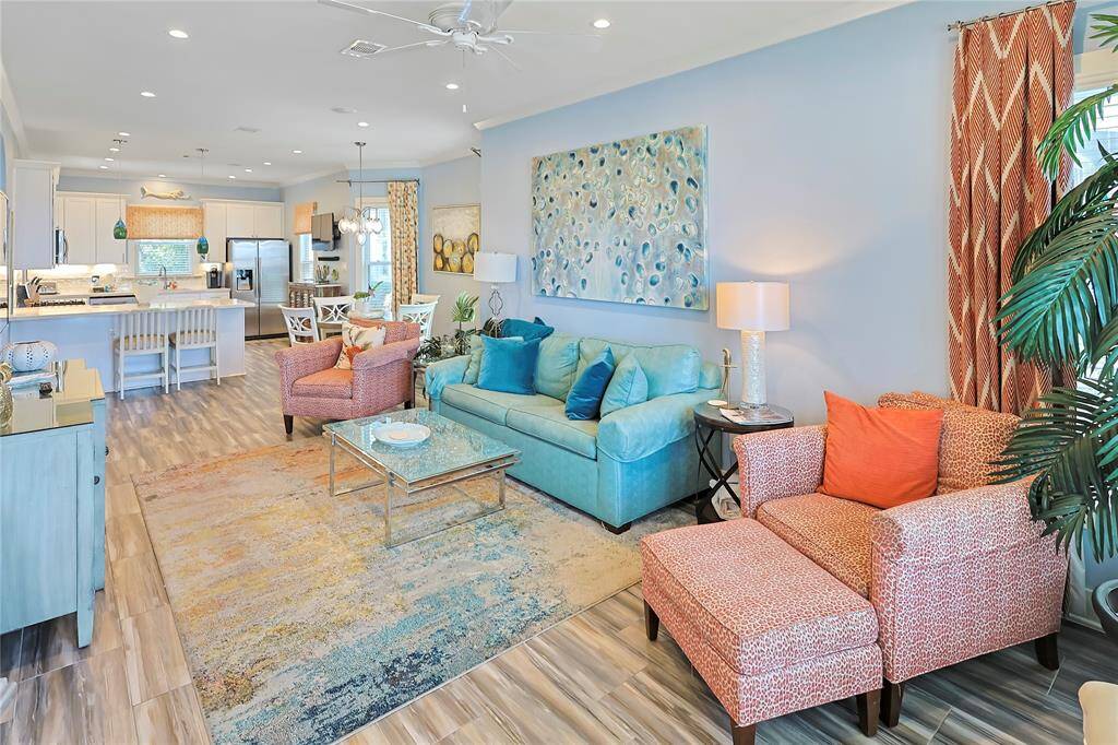 This inviting open-concept living space features modern decor and includes a cozy seating area with vibrant accents. The room is bright and airy, perfect for entertaining or relaxing.